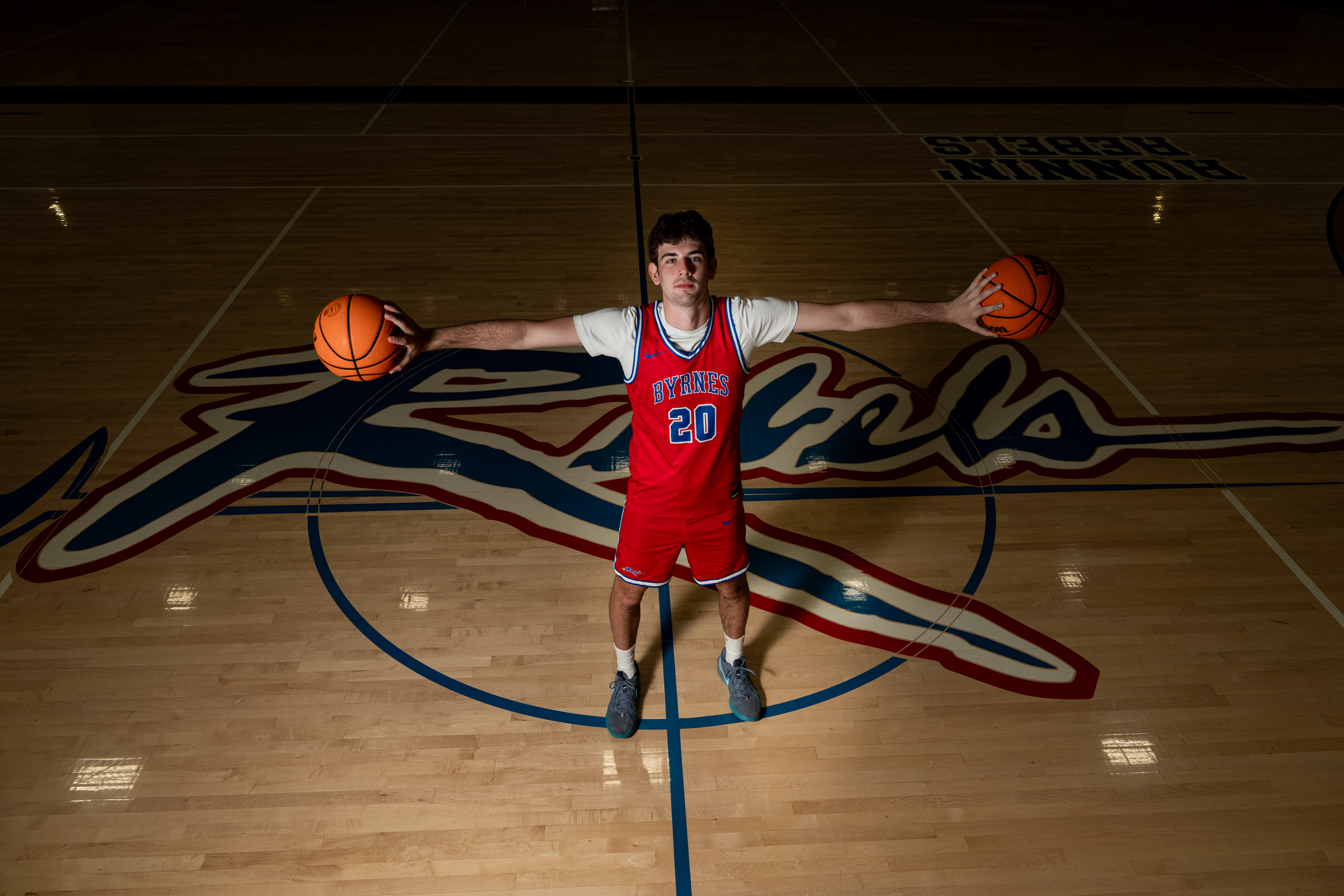 Byrnes high school senior poses with two basketballs on the court for high school senior portraits taken by Taylor Johnson Photography