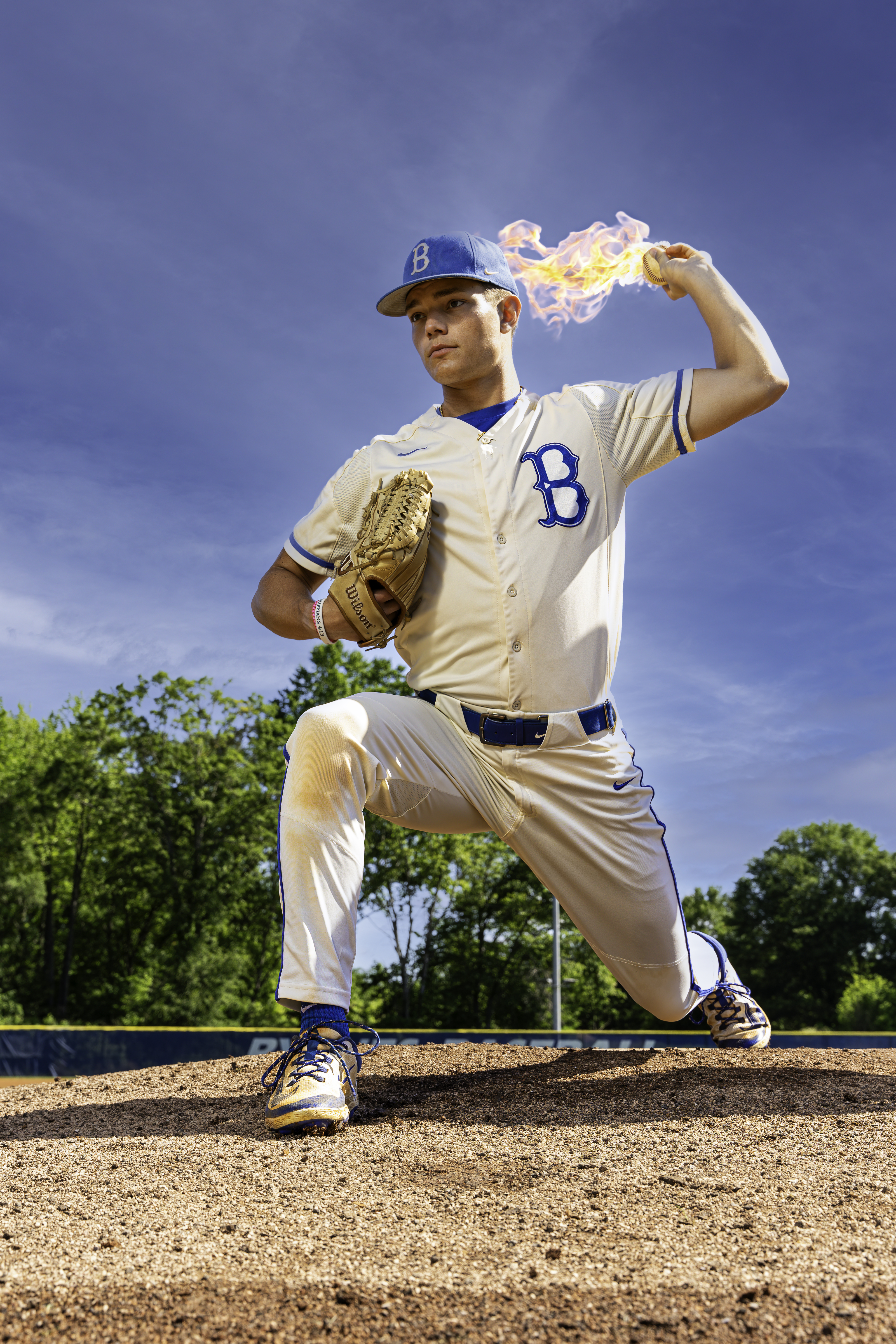 Byrnes Baseball player posing in pitching position for senior pictures holding a baseball on fire taken by Taylor Johnson Photography at the Byrnes Baseball field